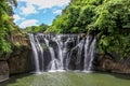 Shifen Waterfalls cascading down a rocky cliff edge into a small, lush pond, Taiwan