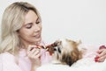 Shih tzu puppy sitting on the blonde shoulder, pink clothes