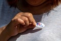 female voter places red white and blue oval I Voted sticker on shirt with right hand after casting Royalty Free Stock Photo