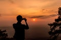 Shilouette of man taking a photo of sunset with smartphone