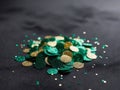 shimmering emerald green and gold confetti quins on a dark background.