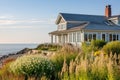 shingle-style home nestled among coastal plants with ocean backdrop