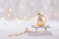 Shining Christmas ball on toy white sled on light bokeh background Royalty Free Stock Photo