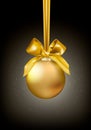 Shining Christmas golden ball hanging on satin ribbon with bow on dark backgroung with light and star dust. Editable