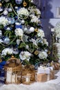 Shining Christmas tree decorated with balls and flowers, gifts and candles in cages under it in living room. Christmas evening. Royalty Free Stock Photo