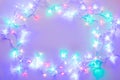 Shining festive multicolor christmas lights frame with copy space, glowing purple and mint color garland