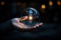 A shining light inside a clear bubble held in a person\'s hand with a dark background Royalty Free Stock Photo