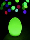 Shining neon green egg shaped table lamp with vibrant bokeh in background