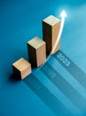 Shining rise up arrow on wooden cube blocks, bar graph chart steps on blue background with year numbers.