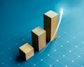 Shining rise up arrow on wooden cube blocks, bar graph chart steps table on blue background.