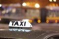 Shining Taxi inscription close up against passing cars on night street of big cit Royalty Free Stock Photo