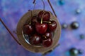 Ripe cherries lie in a wooden vintage box with a pen on a blue background with round glass beads in blur Royalty Free Stock Photo