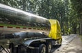 Shiny big rig yellow semi truck with stainless steel tank semi trailer running on the rest area road in forest Royalty Free Stock Photo