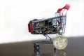 Shiny Bitcoin next to a trolley filled with money
