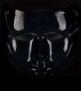 Shiny black mask silhouette on black background. Royalty Free Stock Photo