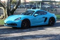 A shiny blue Porsche parked by a tree