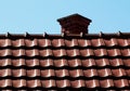 Brown clay tile roof detail at roof ridge with brick chimney Royalty Free Stock Photo