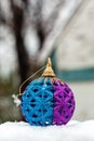 Shiny Christmas ball colored in blue and purple on a white snow outdoor