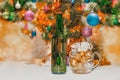 shiny christmas balls in a beer glass next to a green bottle and a decorated new year tree Royalty Free Stock Photo