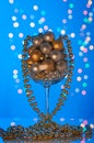 Shiny Christmas ornaments in large glass on blue background.