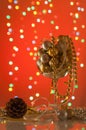 Shiny Christmas ornaments in a large glass on a red background.