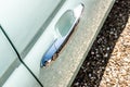 Detailed view of a chrome car door handle seen in bright sunlight.