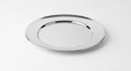 Shiny chrome plate on plain white surface reflecting light evenly Royalty Free Stock Photo