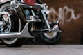 Shiny Chromed Retro Fishtail Exhausted Pipes Of Luxury Motorcycle. Brick Wall With Defocused Graffiti In Background