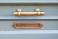 Shiny copper mailbox door handle metal postbox on green blue old-fashioned wooden door in classic design close-up