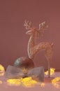 Shiny deer stands next to ball with glitter and bow and Christmas lights on pink background. New Year. Vertical Royalty Free Stock Photo