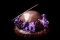 Shiny glazed chocolate and blackberry dessert with purple microwave sponge and fresh berries on black background