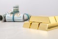 Shiny gold bars and dollar rolls on table Royalty Free Stock Photo