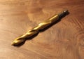 A Shiny Gold Drill Bit on a Wooden Backgound Royalty Free Stock Photo