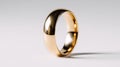 Shiny gold wedding band standing upright on white surface with soft shadow and smooth reflective surface in minimalistic setting Royalty Free Stock Photo