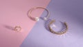 Shiny golden bracelets and chain shape ring on pink and purple background Royalty Free Stock Photo