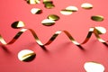 Shiny golden serpentine streamer and confetti on red background, closeup Royalty Free Stock Photo