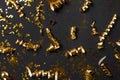 Shiny golden serpentine streamers and confetti on black background, flat lay