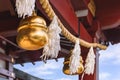 Shiny golden suzu bells hung on a shimenawa straw rope adorned with shide paper in a Shinto shrine.