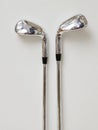 Shiny Golf Irons Stand Side by Side on a Plain Background, Showcasing Their Polished Surface and Sleek Design for Royalty Free Stock Photo
