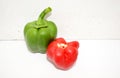 A shiny green bell pepper along with a fresh headless red bell pepper on a white background with their lighting and shadows