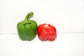 A shiny green bell pepper next to a bright red bell pepper on a white background Royalty Free Stock Photo