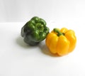 A shiny green bell pepper next to a fresh yellow bell pepper with different angles on a white background Royalty Free Stock Photo