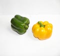 A shiny green bell pepper next to a yellow bell pepper on a white background Royalty Free Stock Photo