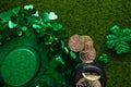 Shiny hat of leprechaun with clover and coins on green grass background. St. Patrick`s Day celebration. Flat lay. View from above Royalty Free Stock Photo