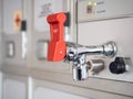 Shiny hot water tap with red lever in aircraft galley. Royalty Free Stock Photo