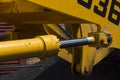 Shiny hydraulic cylinder rod of yellow road machinery close-up