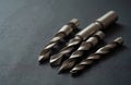 Shiny metal drill bits of varying sizes on dark textured surface. Sharp tools process holes in metal, wood, concrete. Essential Royalty Free Stock Photo
