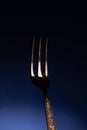 Shiny metal fork with three prongs on blue Royalty Free Stock Photo