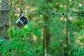 A shiny metal mug is hanging on a hook in the woods by a tree. A rope is stretched between the trees around the tent camp. Tourist Royalty Free Stock Photo