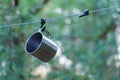 A shiny metal mug is hanging on a hook in the woods by a tree. A rope is stretched between the trees around the tent camp. Tourist Royalty Free Stock Photo